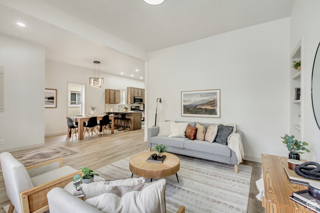 Living room with light wood-style floors, recessed lighting, built in features, and baseboards