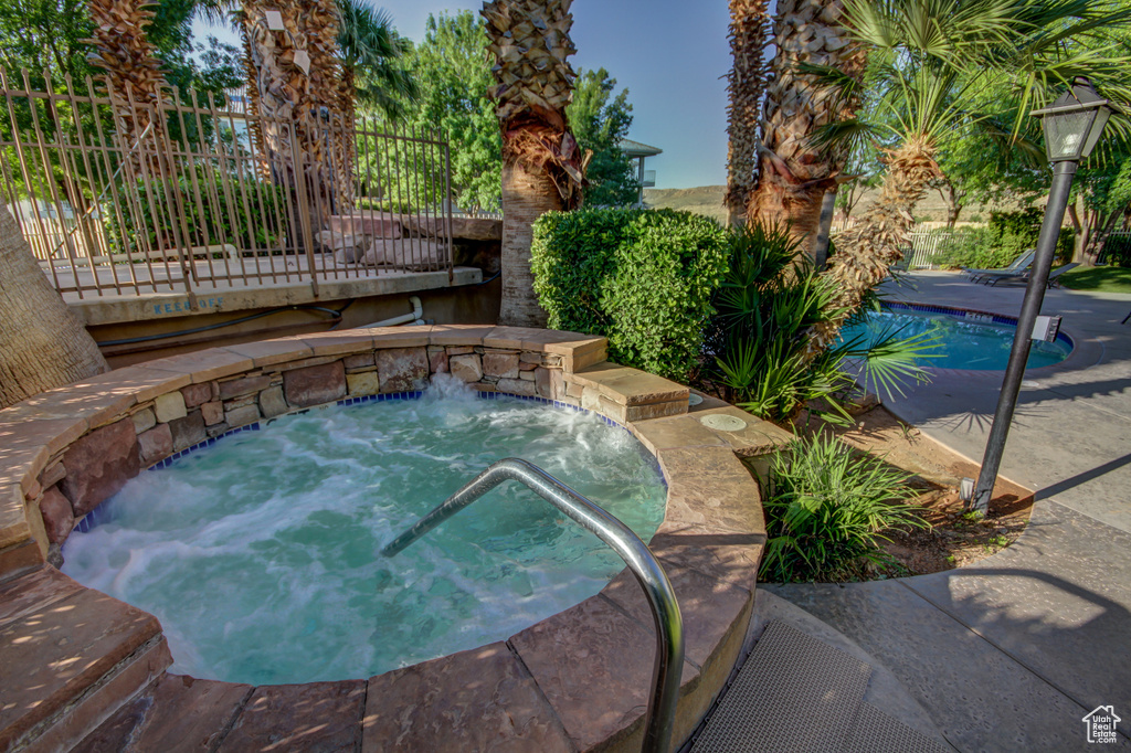 View of swimming pool with an in-ground hot tub and fence
