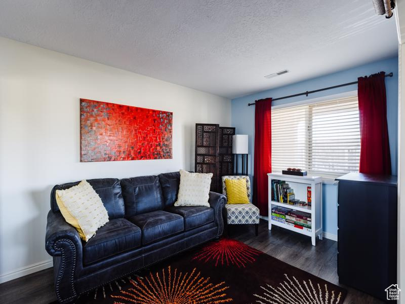 Living room with dark wood-style floors, baseboards, and a textured ceiling