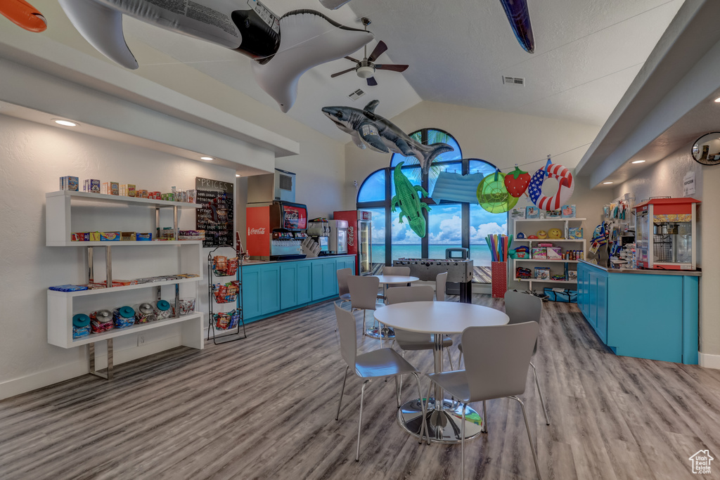 Dining area with wood finished floors, high vaulted ceiling, baseboards, and a ceiling fan