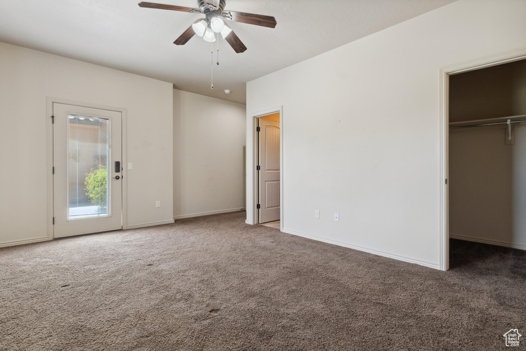 Unfurnished bedroom with carpet flooring, a walk in closet, baseboards, a ceiling fan, and a closet