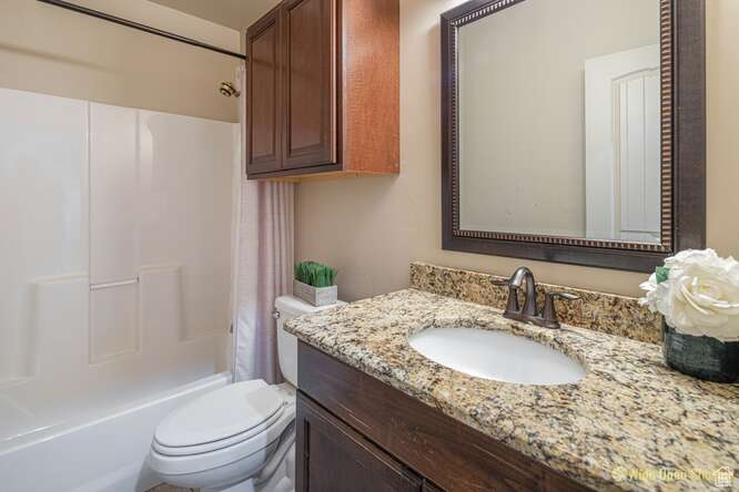Full bathroom with toilet, vanity, and shower / tub combo