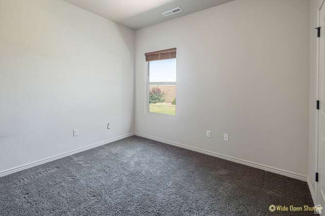 Unfurnished room with dark carpet and baseboards