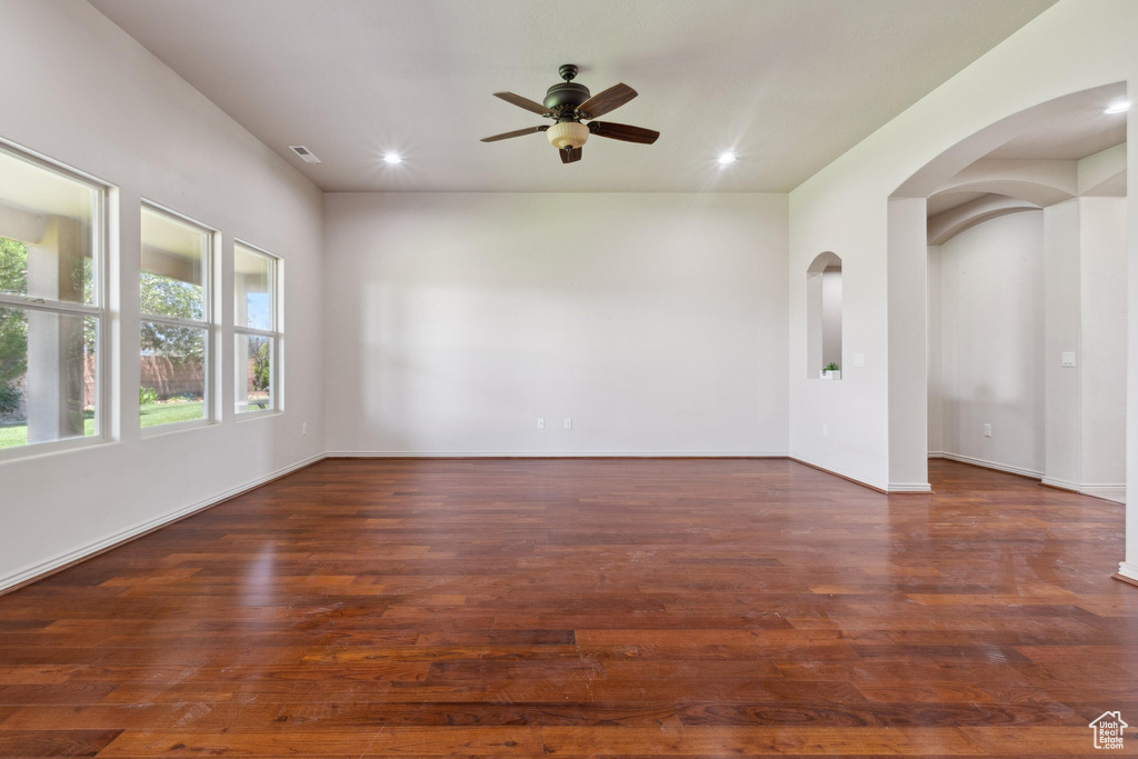Empty room featuring a ceiling fan, arched walkways, recessed lighting, wood finished floors, and baseboards