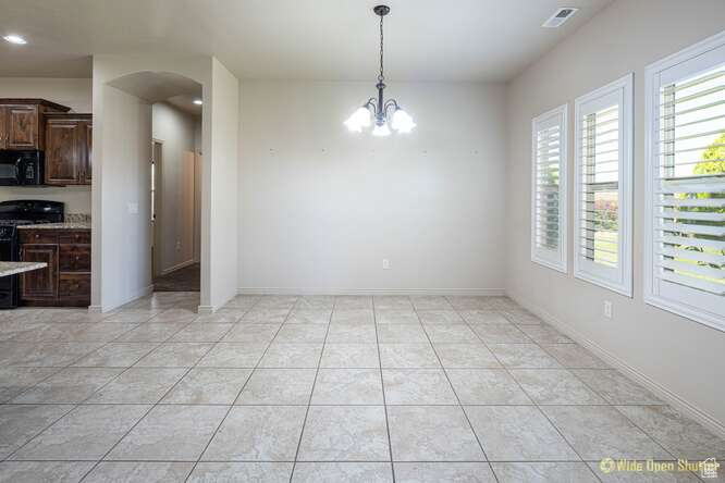 Unfurnished dining area featuring arched walkways, a chandelier, light tile patterned flooring, and recessed lighting