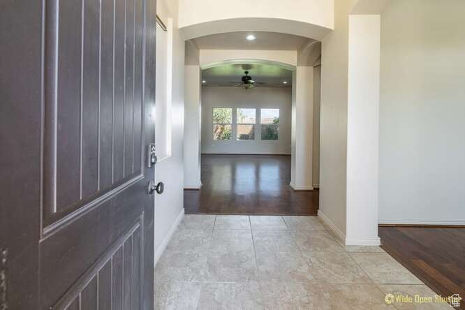 Corridor with arched walkways, baseboards, and light tile patterned flooring