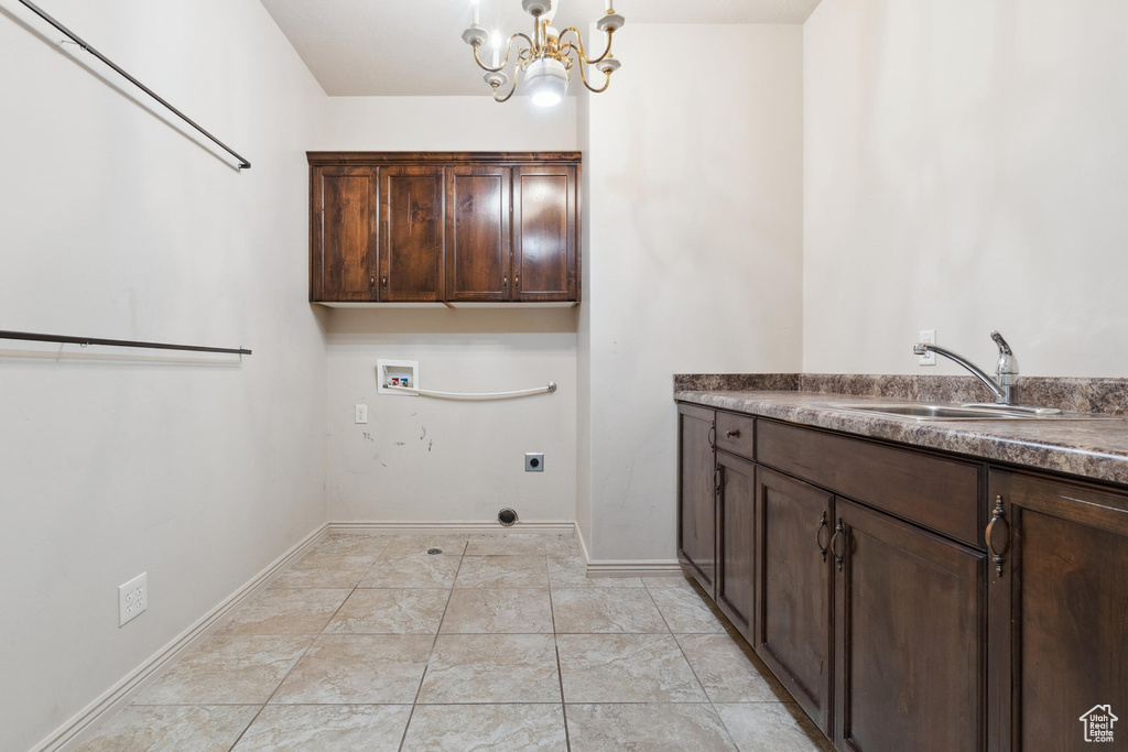 Laundry area featuring electric dryer hookup, cabinet space, hookup for a washing machine, a chandelier, and baseboards