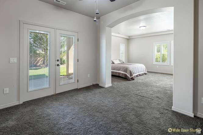 Bedroom featuring access to outside, arched walkways, french doors, and dark carpet