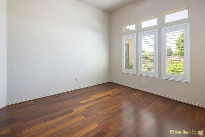 Unfurnished room featuring dark wood-style flooring and baseboards