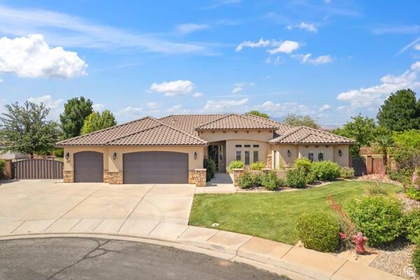 Mediterranean / spanish-style house with stucco siding, stone siding, a garage, concrete driveway, and a tile roof