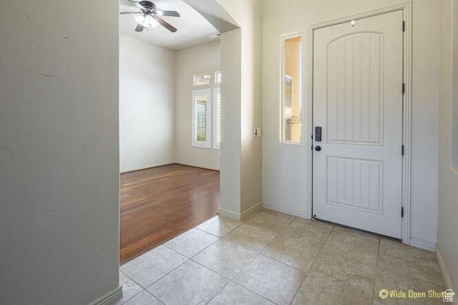 Foyer entrance with a ceiling fan, baseboards, and light tile patterned floors