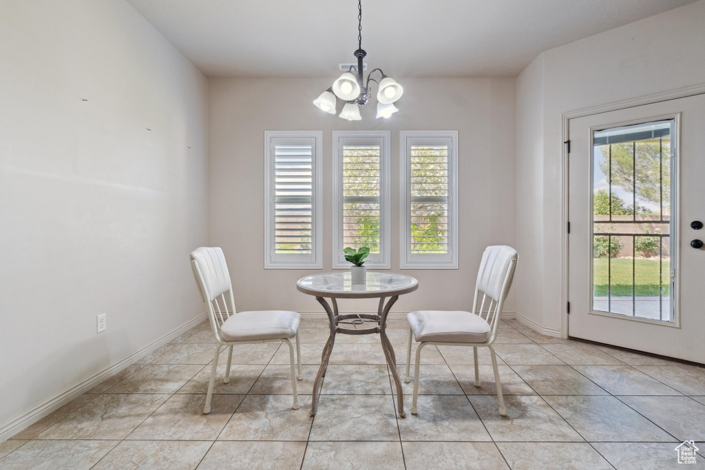 Dining room with a chandelier, light tile patterned flooring, and baseboards