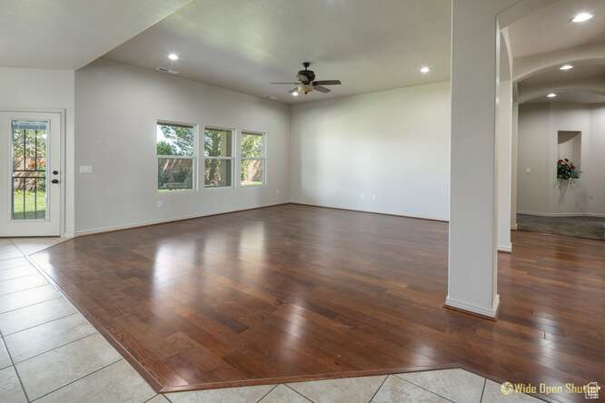 Unfurnished living room with a ceiling fan, wood finished floors, arched walkways, recessed lighting, and baseboards