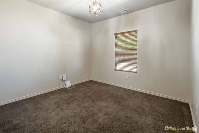 Unfurnished room with dark carpet, a chandelier, and baseboards