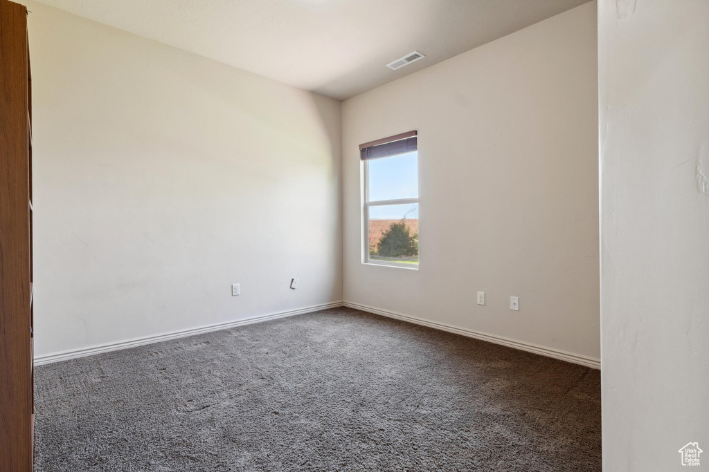 Spare room with dark colored carpet and baseboards