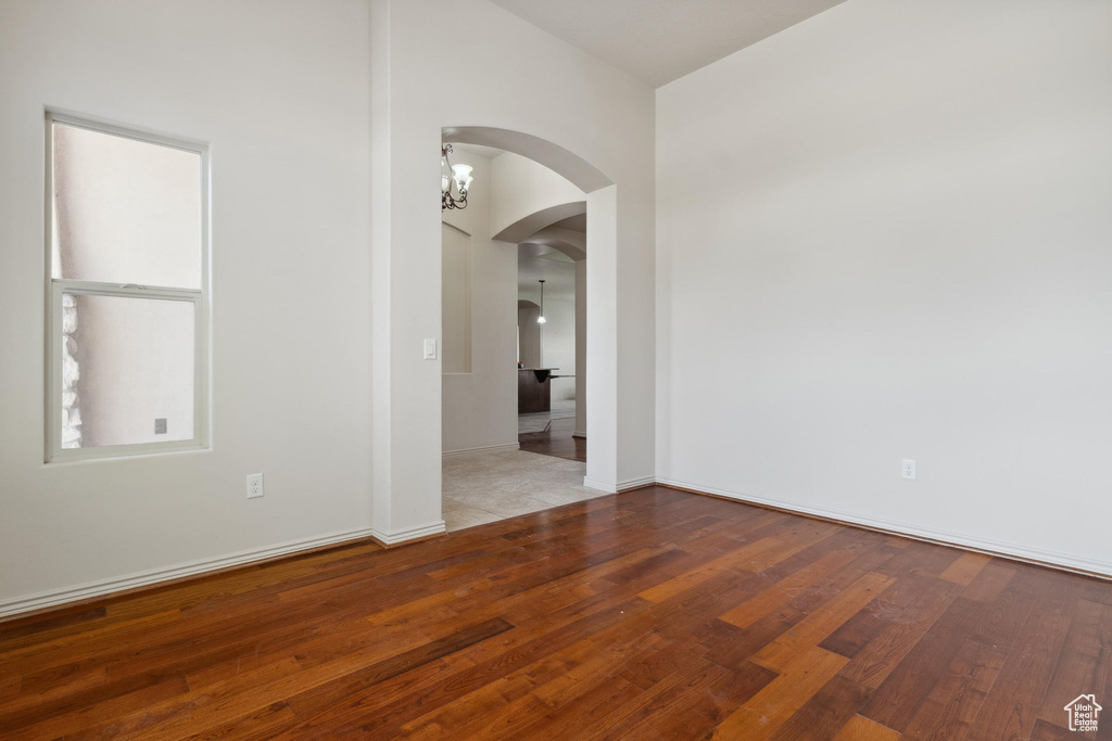 Empty room featuring arched walkways, wood finished floors, and baseboards