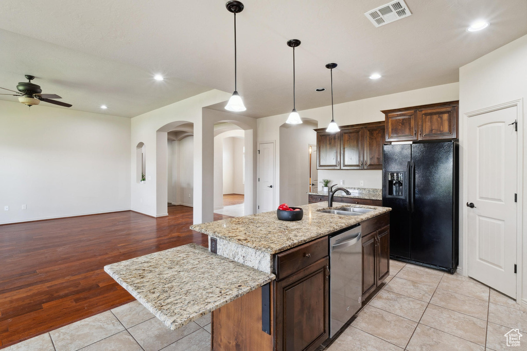 Kitchen featuring black fridge with ice dispenser, dishwasher, a sink, a ceiling fan, and arched walkways
