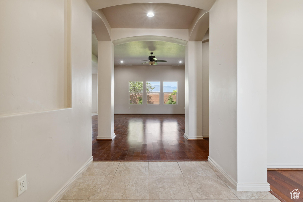 Corridor featuring arched walkways, wood finished floors, baseboards, and recessed lighting
