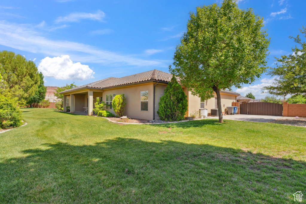 Back of house featuring stucco siding, a gate, and a tiled roof