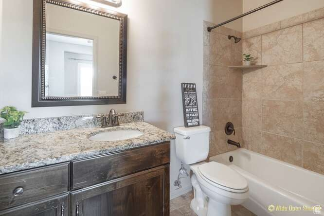 Bathroom featuring vanity, toilet, and shower / washtub combination