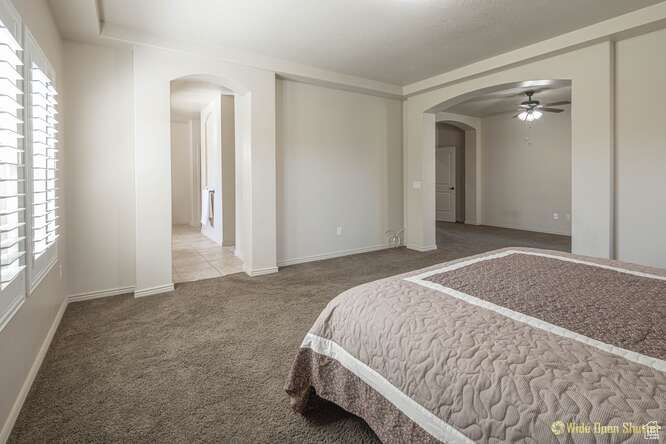 Carpeted bedroom with arched walkways, multiple windows, and baseboards