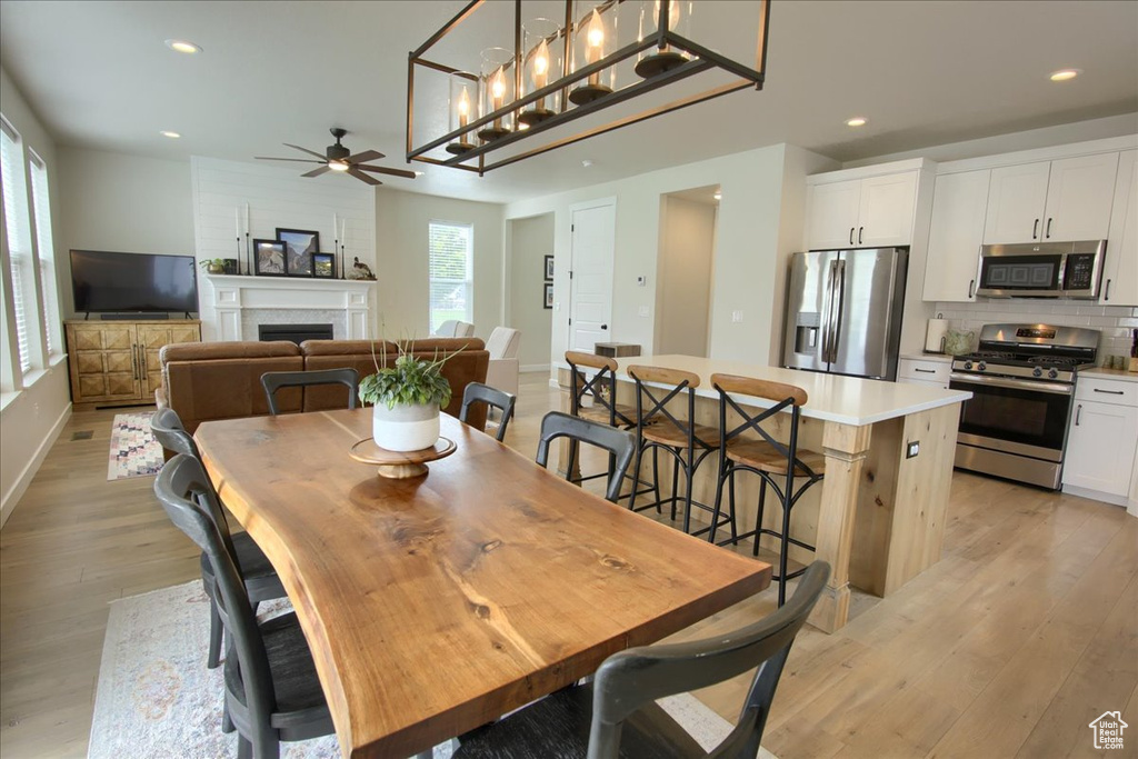 Dining space featuring ceiling fan, light wood-style floors, a fireplace, recessed lighting, and baseboards
