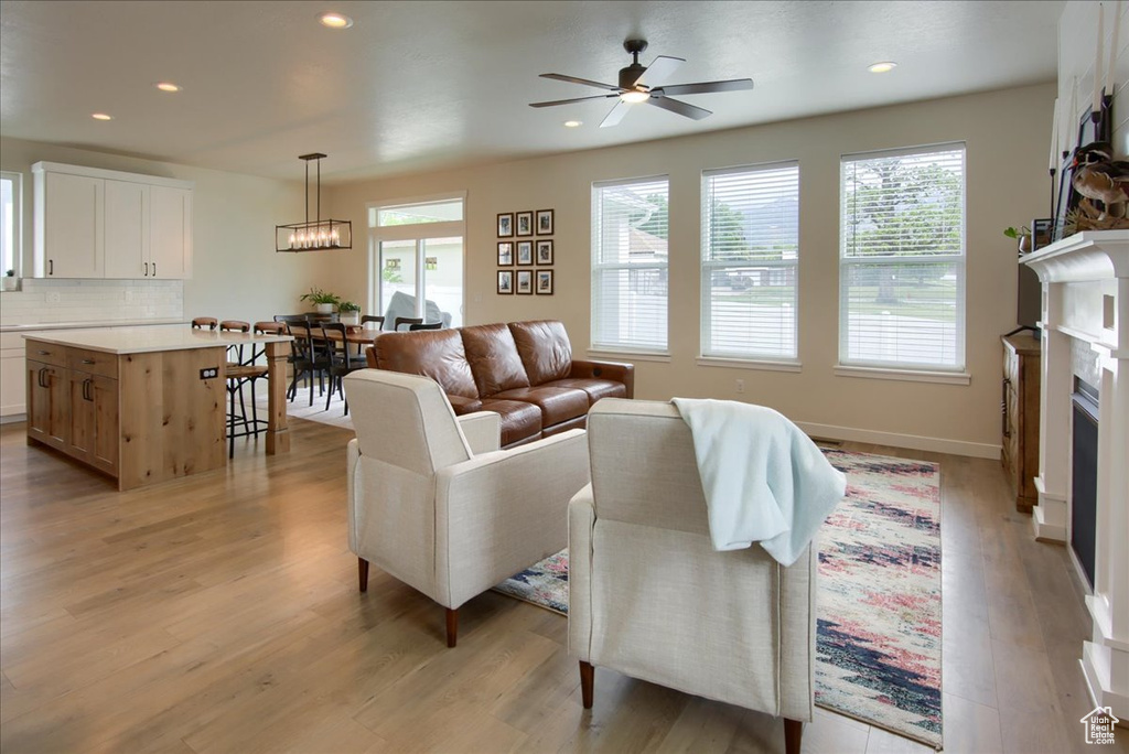 Living area featuring plenty of natural light, light wood-style floors, ceiling fan, a fireplace, and recessed lighting