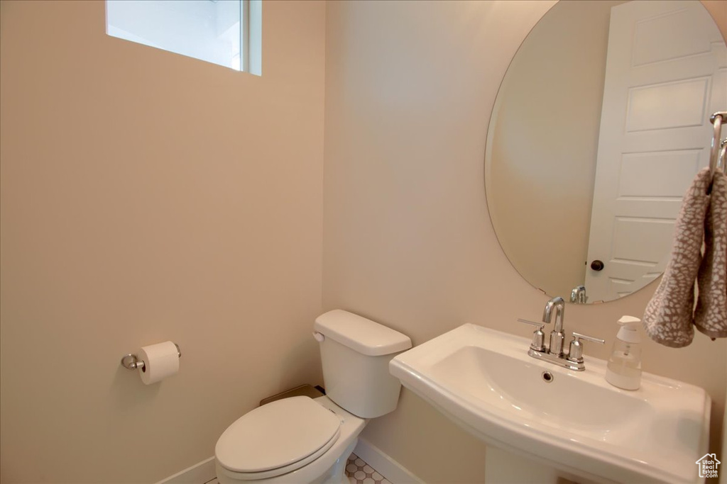 Bathroom featuring toilet, a sink, and baseboards