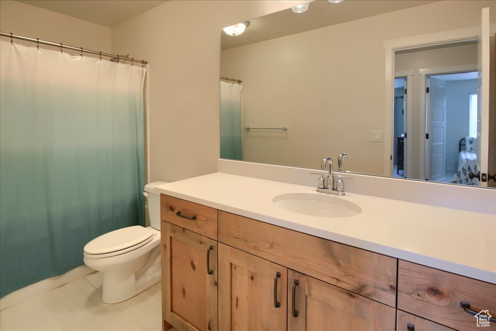 Bathroom with toilet, vanity, tile patterned flooring, and a shower with curtain