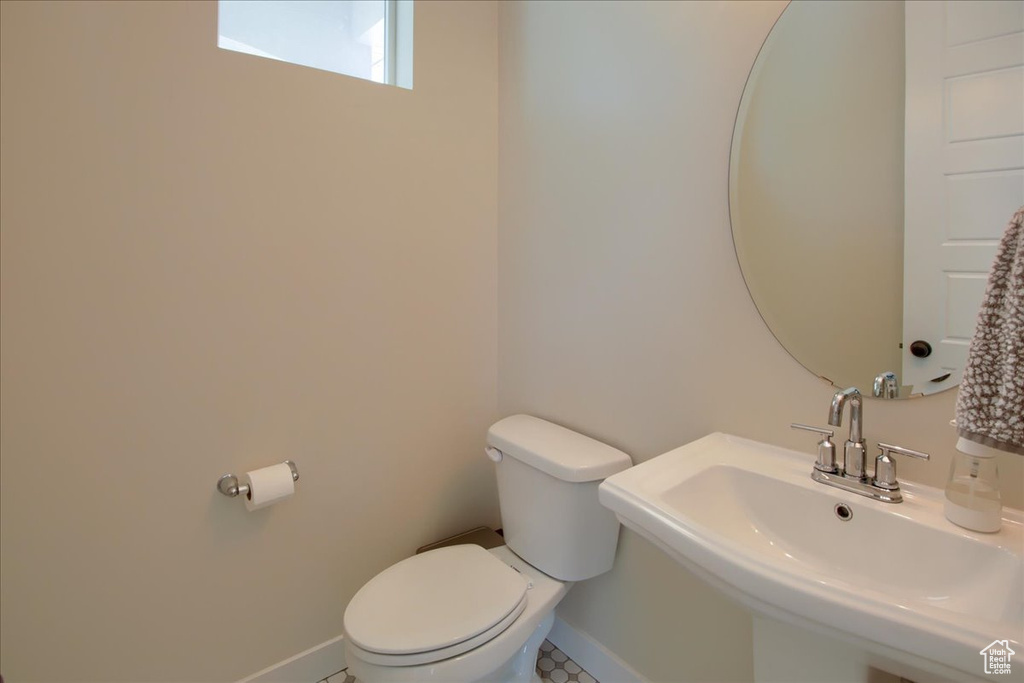 Bathroom featuring a sink, toilet, and baseboards