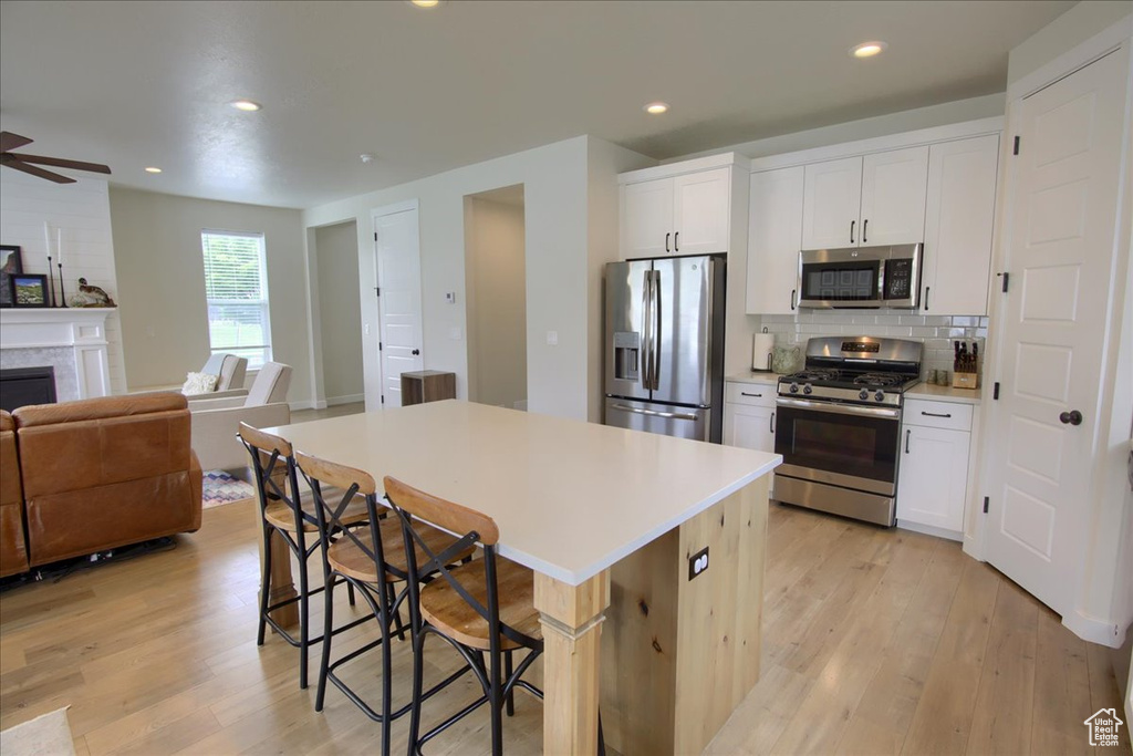 Kitchen with stainless steel appliances, open floor plan, a kitchen bar, a kitchen island, and light wood-style flooring