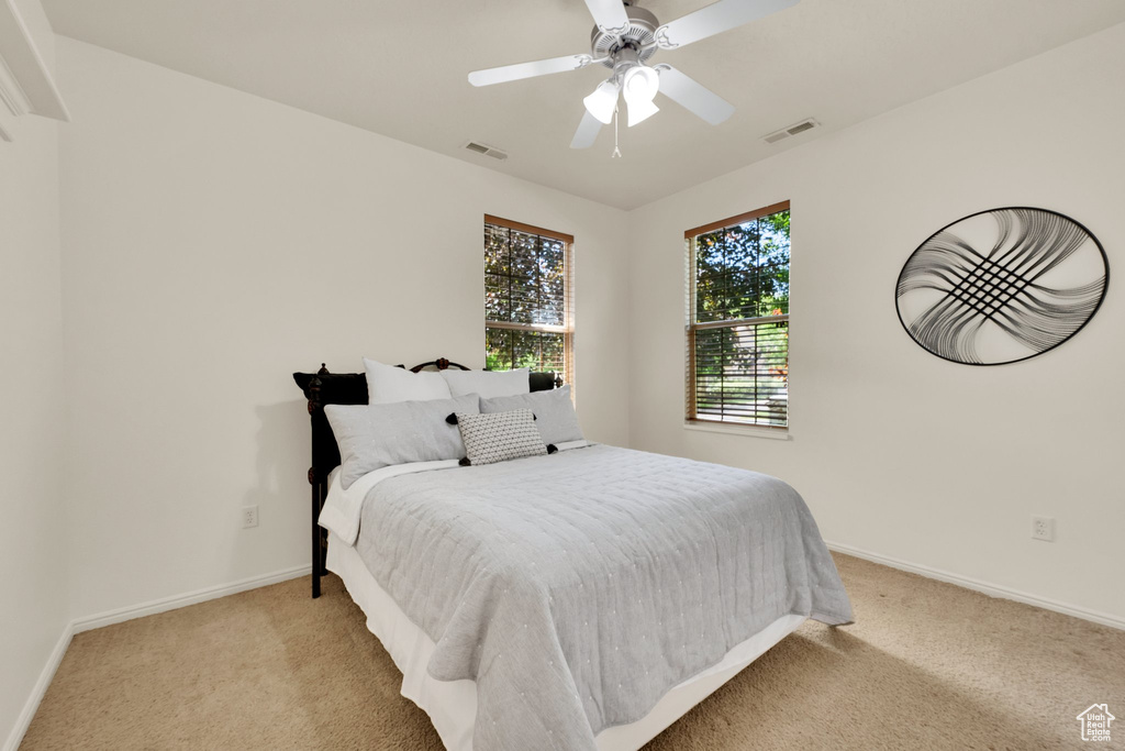 Bedroom with light carpet, baseboards, and a ceiling fan