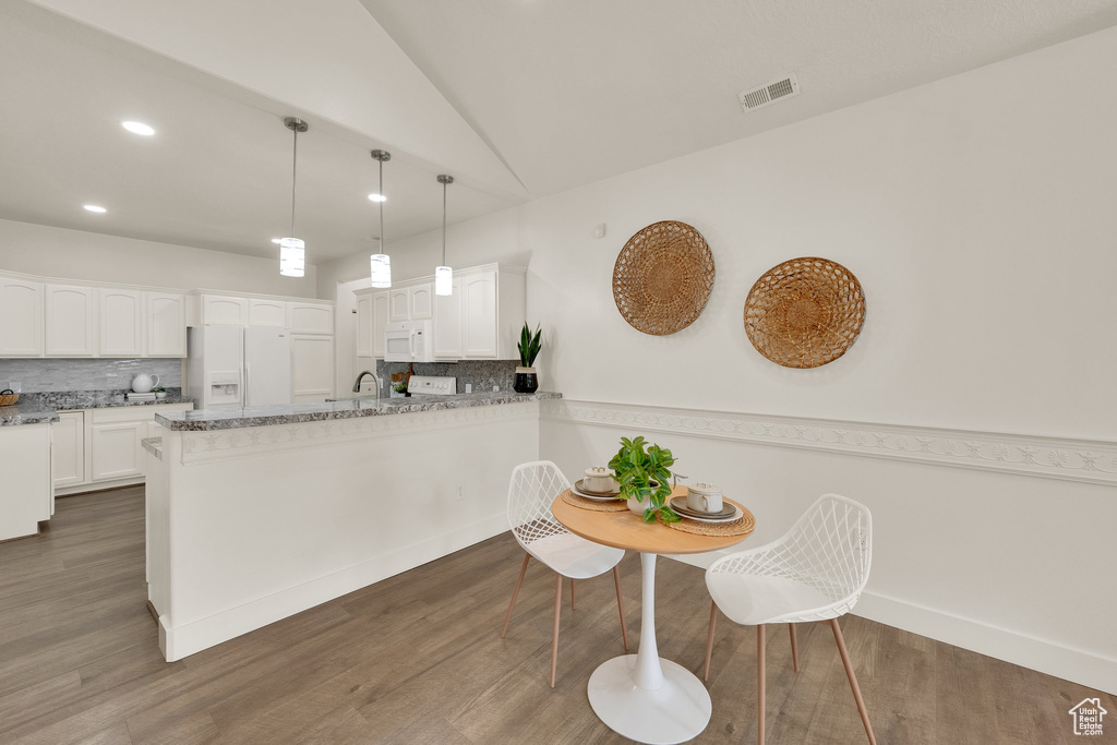 Kitchen featuring white appliances, decorative backsplash, white cabinetry, recessed lighting, and lofted ceiling
