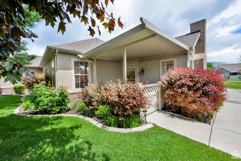 Ranch-style home featuring a chimney, stucco siding, a front lawn, and a shingled roof