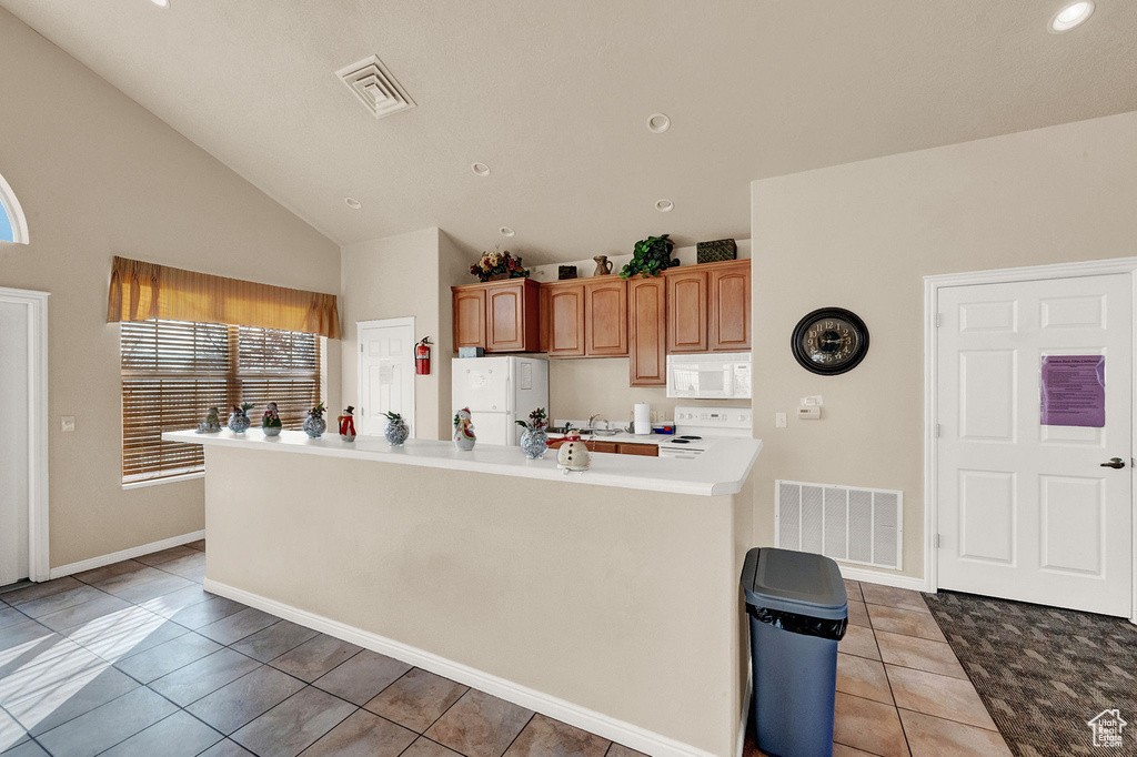 Kitchen featuring white appliances, light tile patterned floors, vaulted ceiling, light countertops, and recessed lighting