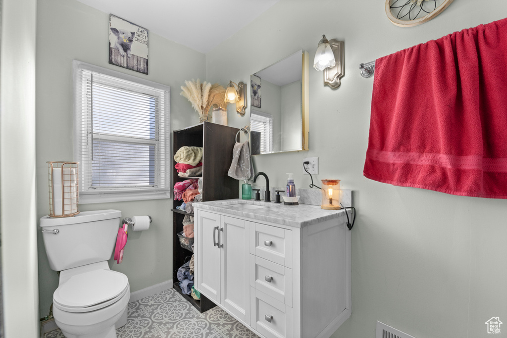 Bathroom with plenty of natural light, vanity, baseboards, and toilet