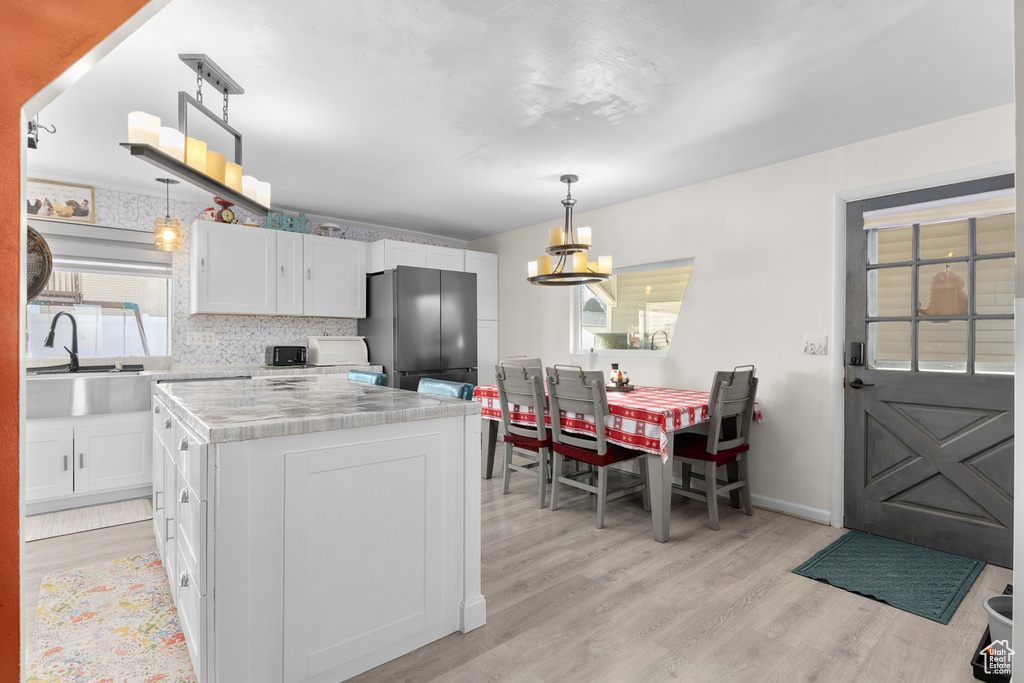 Kitchen featuring freestanding refrigerator, light wood finished floors, a sink, and light countertops