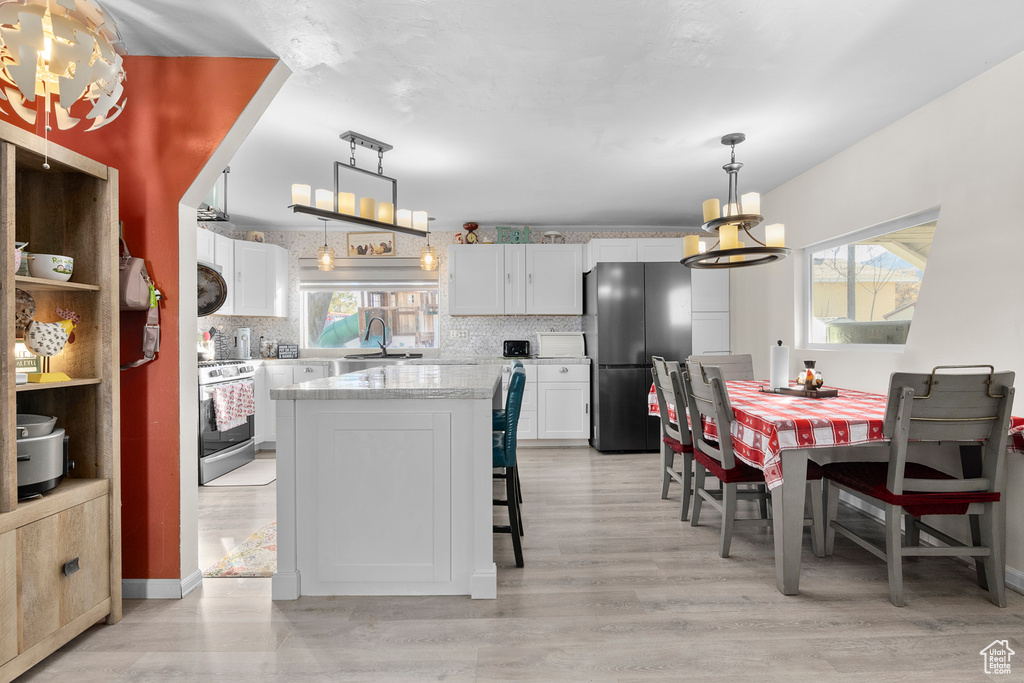 Kitchen featuring range with gas cooktop, a chandelier, freestanding refrigerator, and healthy amount of natural light