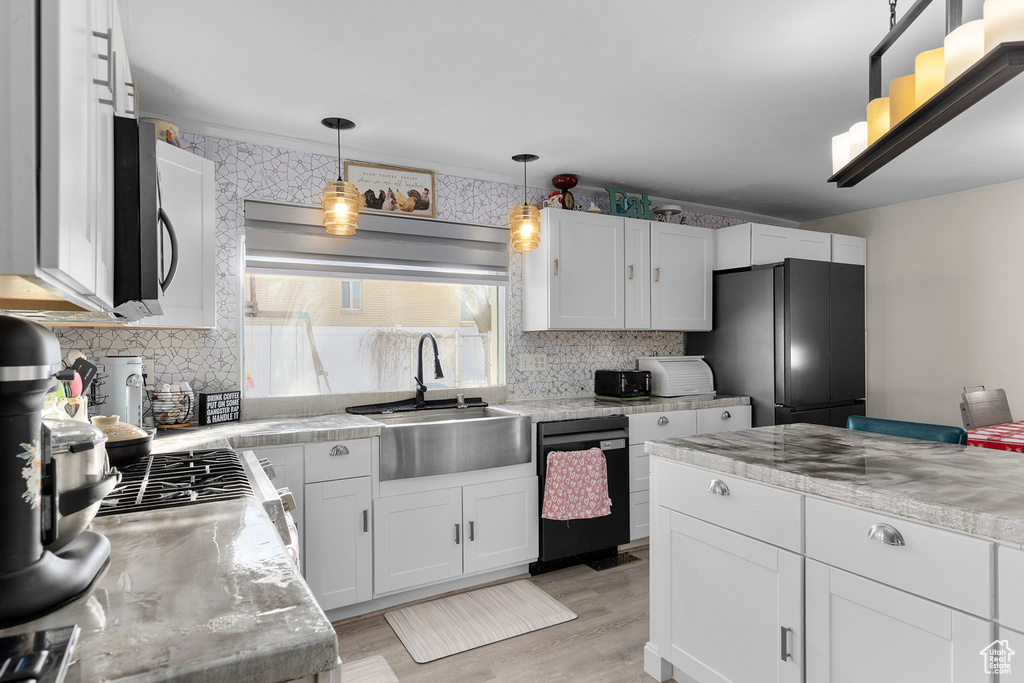Kitchen with freestanding refrigerator, dishwasher, a sink, light countertops, and white cabinetry