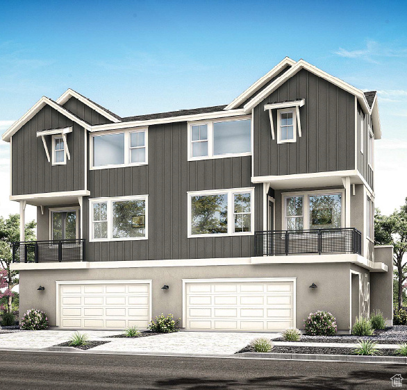View of front of property with a garage, driveway, a balcony, and board and batten siding
