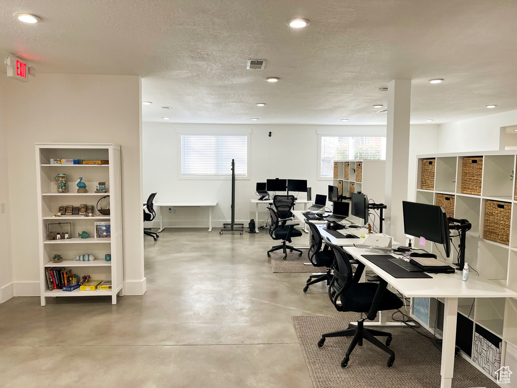 Office area with concrete floors, recessed lighting, baseboards, and a textured ceiling