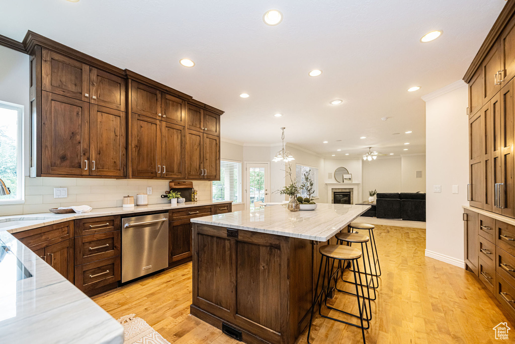 Kitchen featuring stainless steel dishwasher, recessed lighting, a center island, open floor plan, and light stone countertops