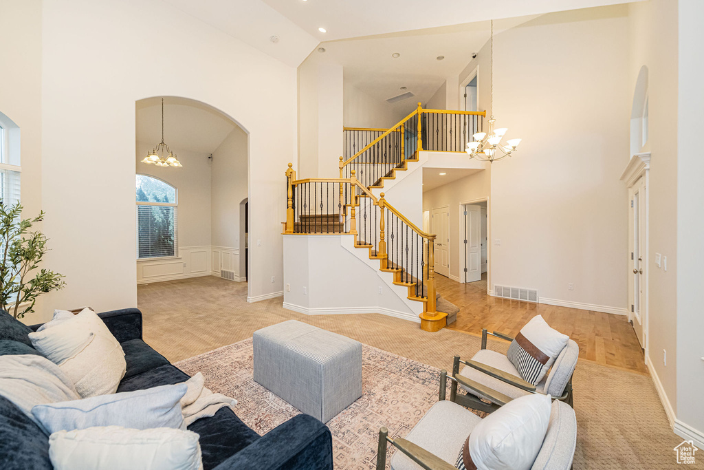 Carpeted living room featuring a chandelier, arched walkways, a high ceiling, stairway, and recessed lighting