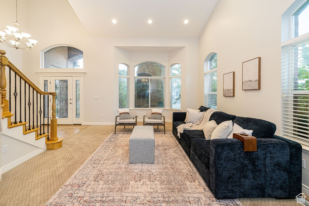 Carpeted living room with a high ceiling, a chandelier, stairway, baseboards, and recessed lighting