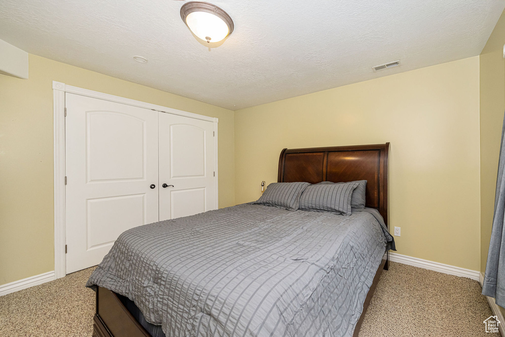 Bedroom with light colored carpet, baseboards, and a closet