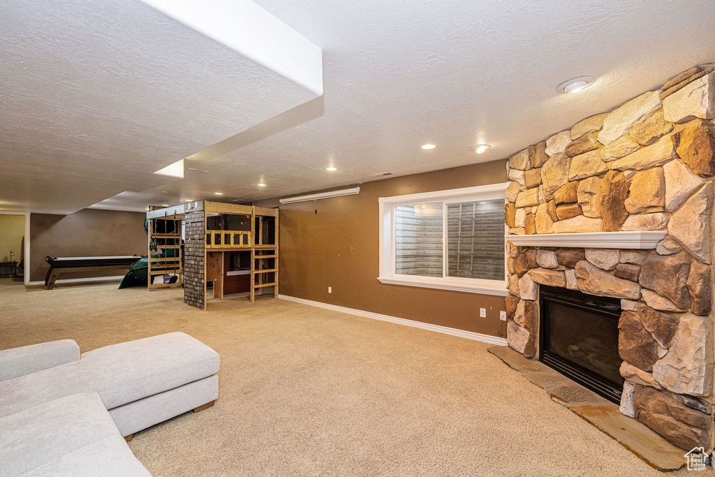 Living area with a fireplace, carpet, a textured ceiling, baseboards, and recessed lighting