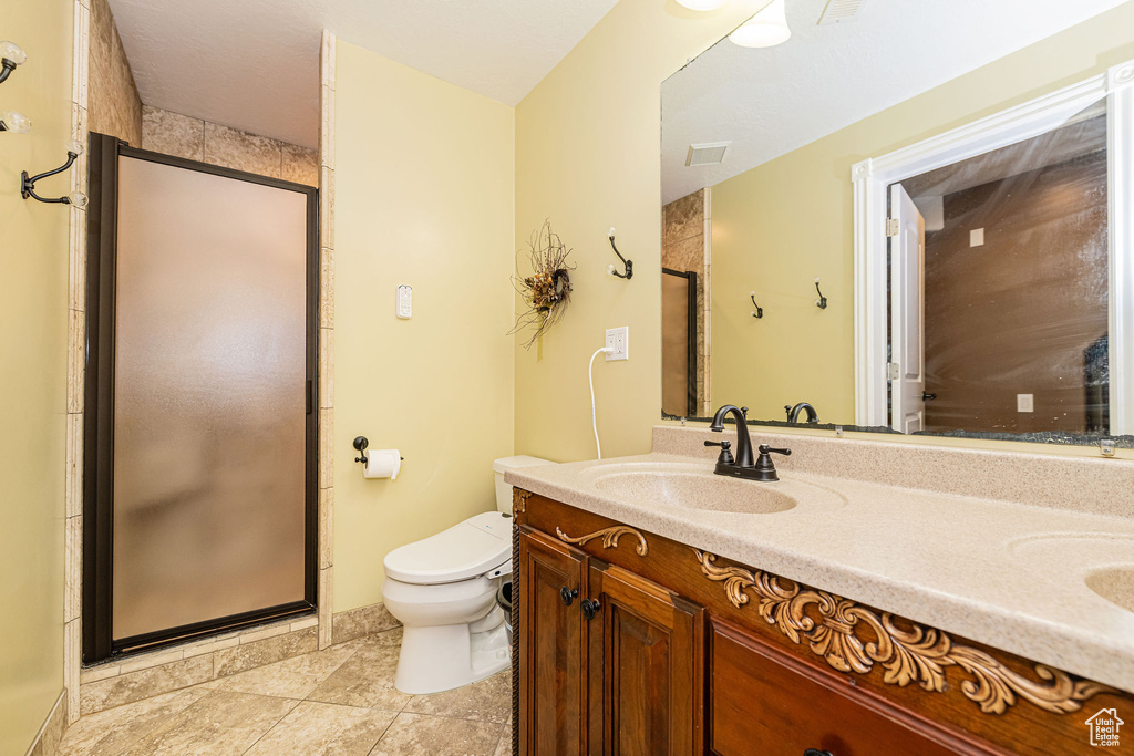 Full bath with a stall shower, toilet, and double vanity