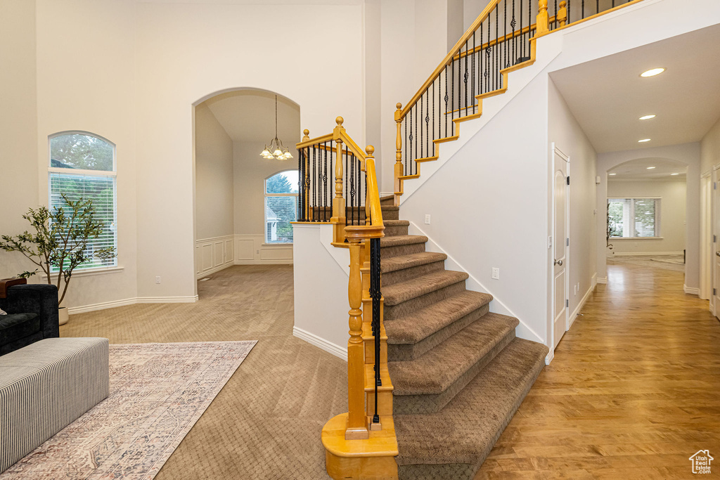 Stairway featuring arched walkways, a high ceiling, a chandelier, recessed lighting, and baseboards