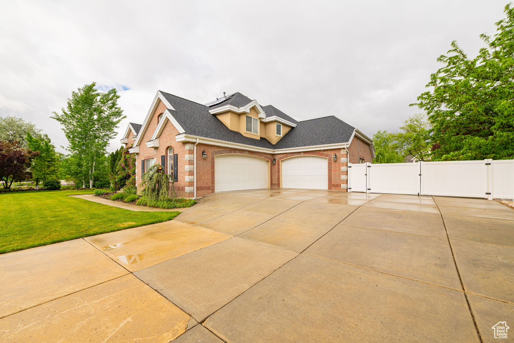 View of front of home with a gate, brick siding, an attached garage, and concrete driveway