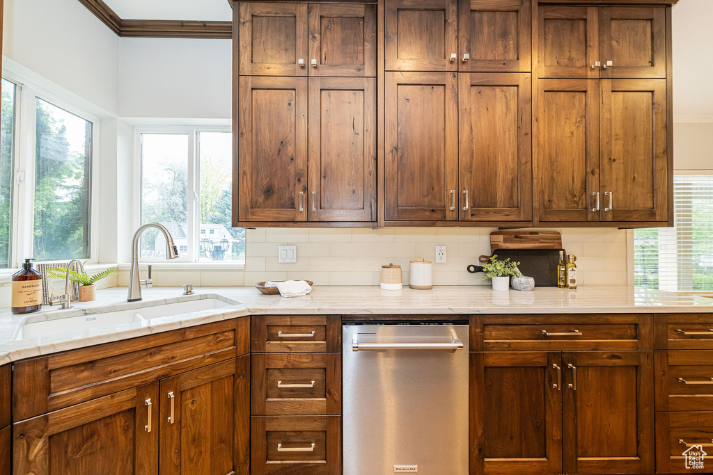 Kitchen featuring dishwasher, a sink, backsplash, light stone countertops, and ornamental molding